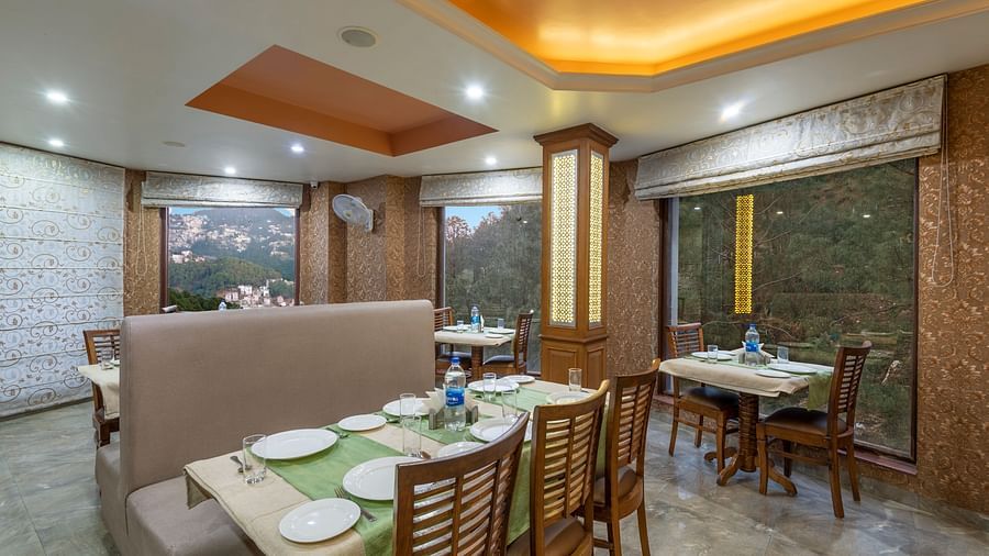 Dining area with a table set for a meal, featuring plates and water bottles, with a mountain view visible through the window at DLS Hotels The Rock Castle.